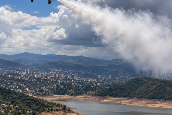 avión sembrador sobre valle y embalse