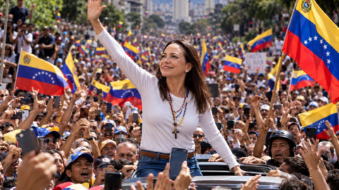 mujer saludando entre banderas venezolanas